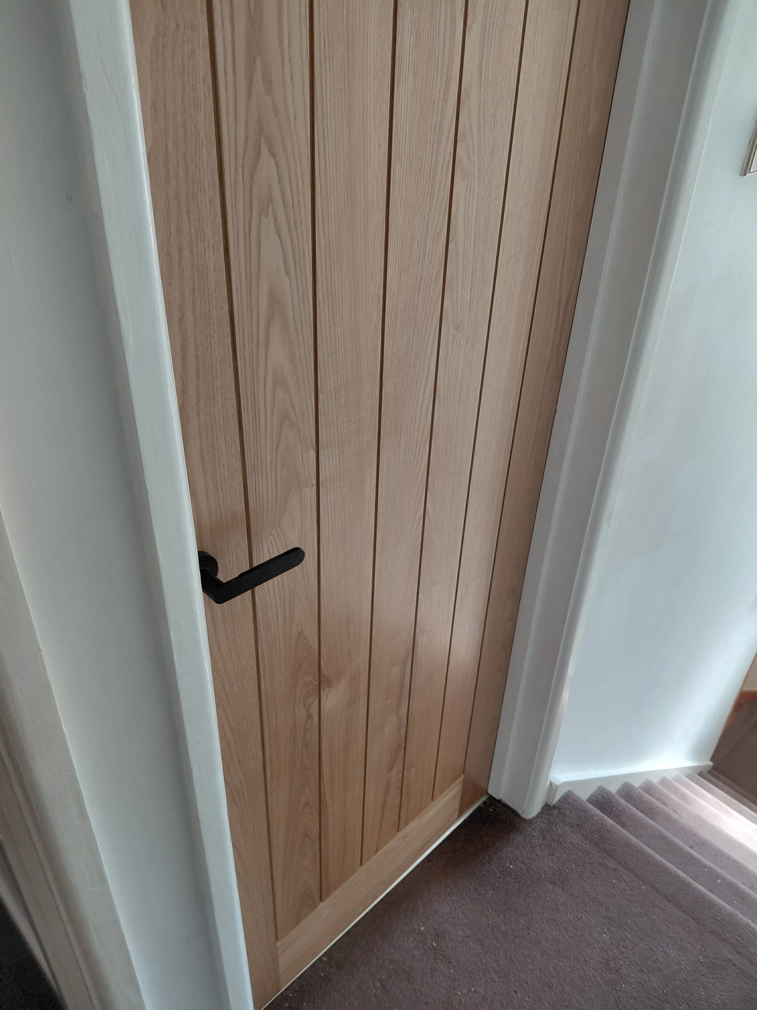 Light oak cottage-style bedroom door with matte black handle
