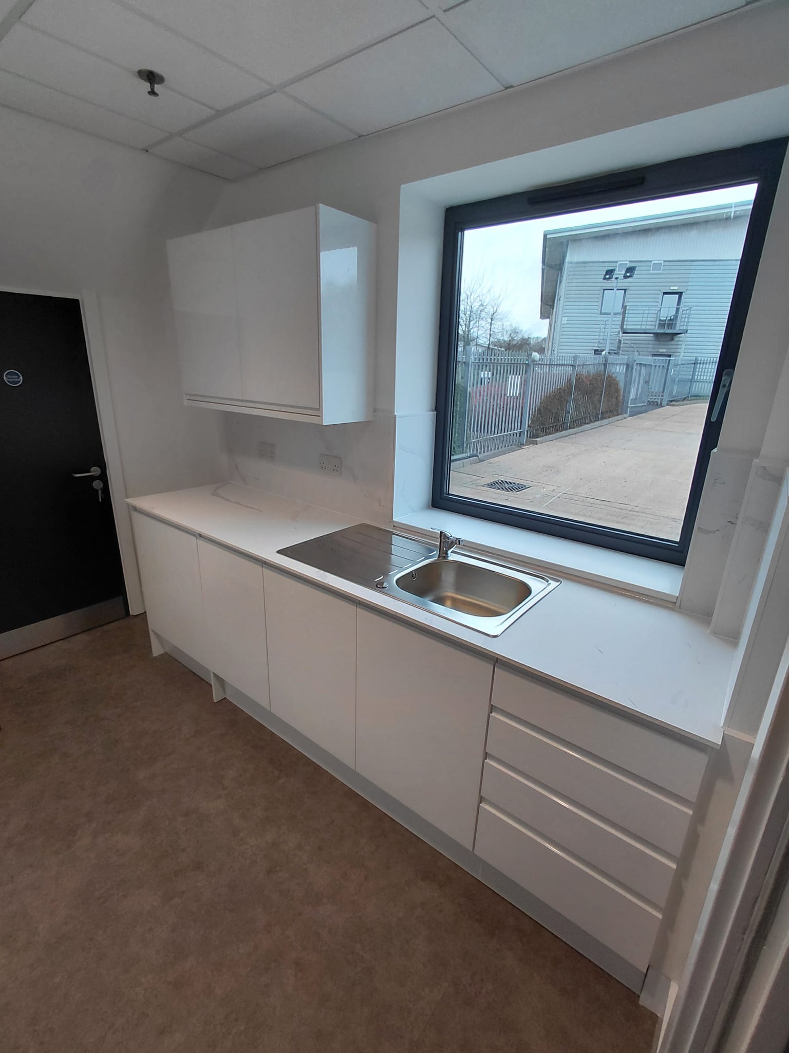 Recently fitted white handleless kitchen with marble-effect worktop and inset sink