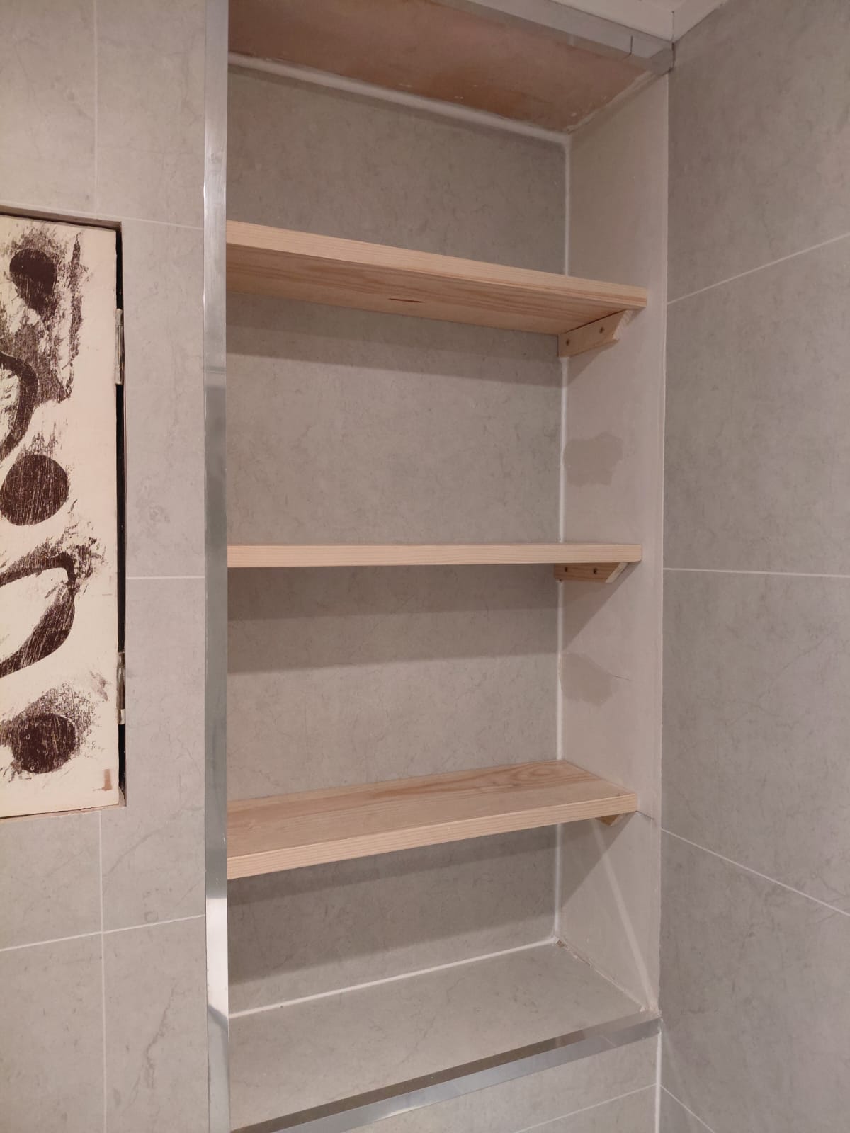 Recessed timber shelves built into a tiled alcove